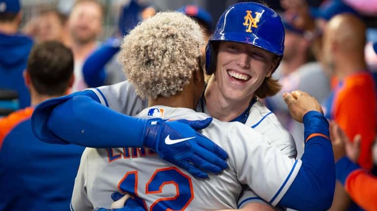 The Mets' Francisco Lindor, back to camera, celebrates with Brett...
