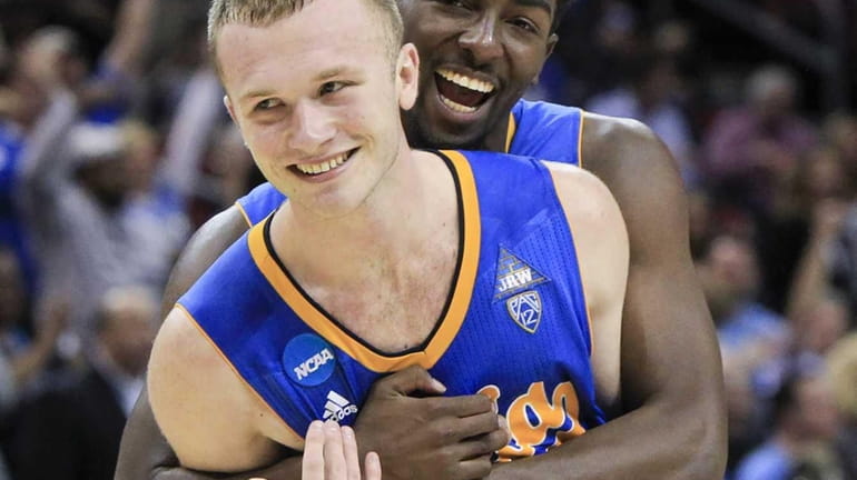 UCLA guard Bryce Alford is hugged by guard Isaac Hamilton...