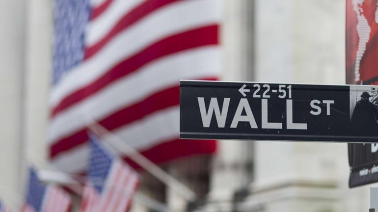 A Wall Street sign hangs near the New York Stock...