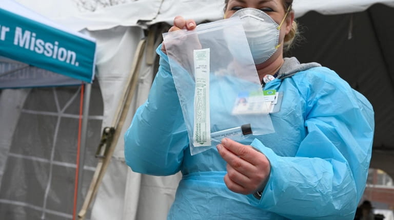 Registered nurse Kristen Monteiro shows a coronavirus testing kit at the...