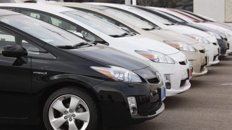 A line of Toyota Prius sedans sit at a Toyota...