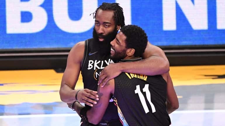 Nets guard James Harden and guard Kyrie Irving embrace during...