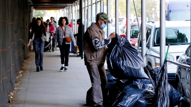 A man puts out trash bags on a Manhattan sidewalk in...