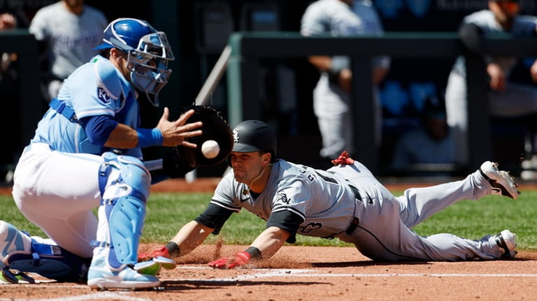 Chicago White Sox' Andrew Benintendi, right, scores off a Dominic...