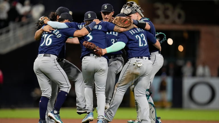 Members of the Seattle Mariners dance in a circle after...
