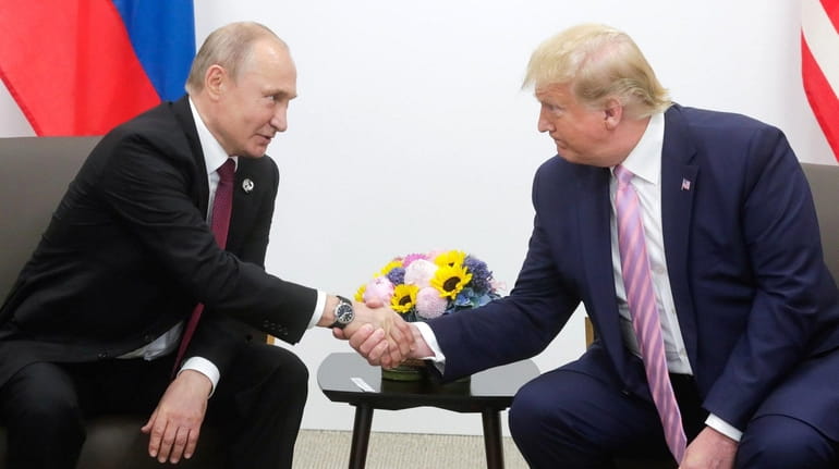 Russian President Vladimir Putin  shaking hands with President Donald J....
