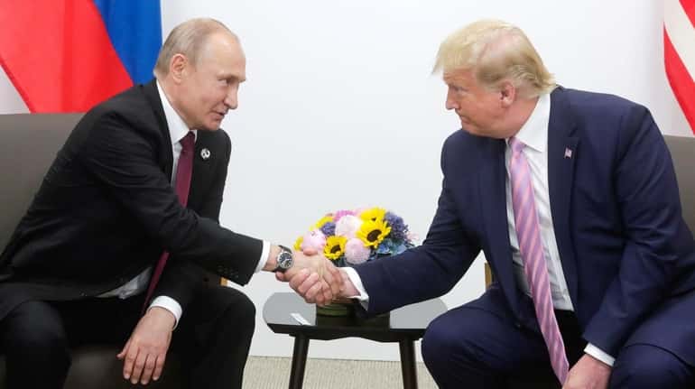 Russian President Vladimir Putin  shaking hands with President Donald J....