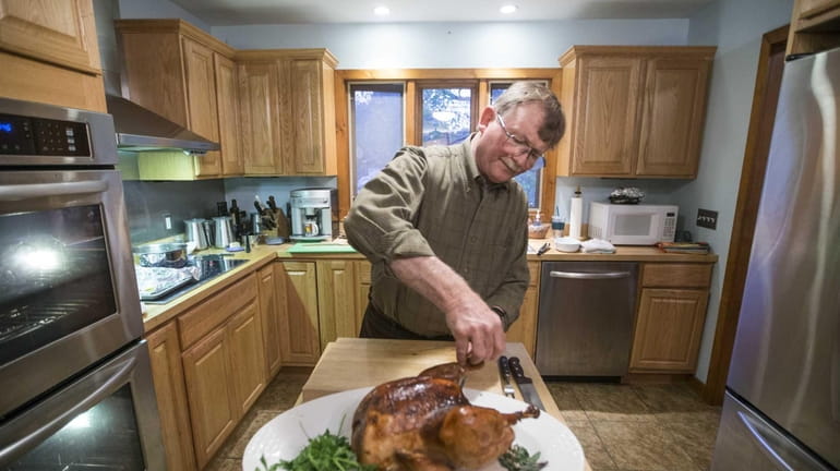 John Ross carves a roasted turkey at his home in...
