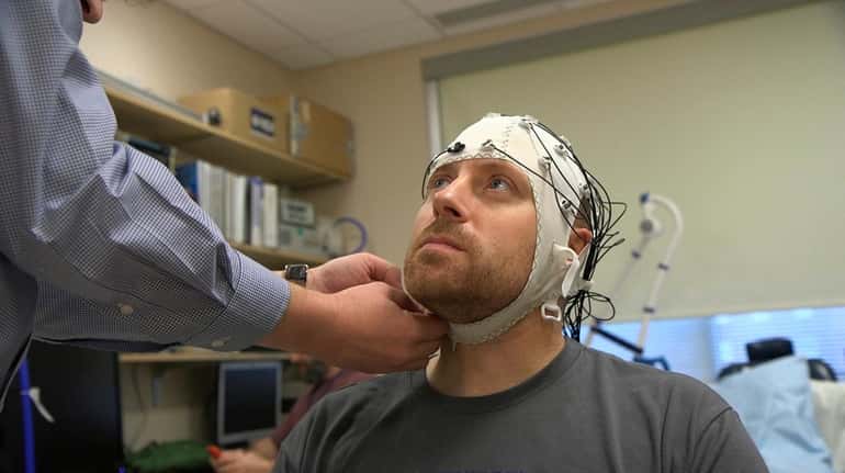 Zach Ault is fitted with an EEG cap which uses...