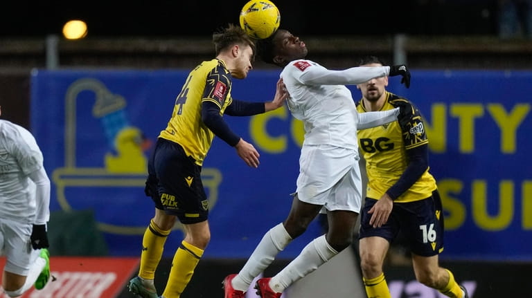Oxford's Lewis Bate, left, and Arsenal's Eddie Nketiah jump for...