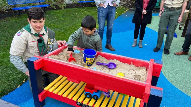 Max McConville shows his Eagle Scout project, a sandbox, to Rudra...
