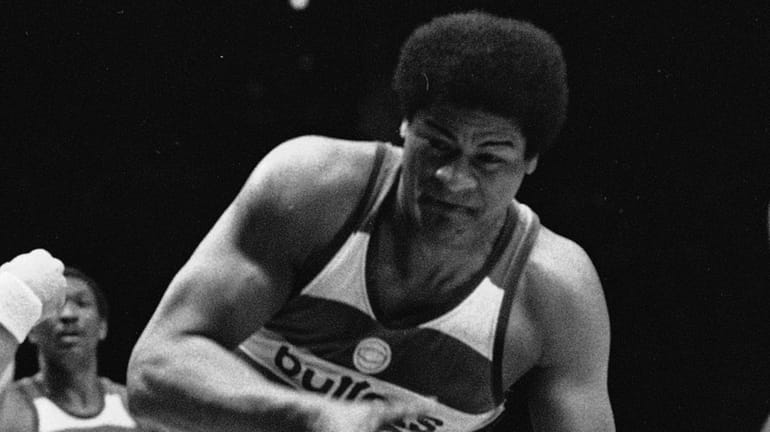 The Bullets' Wes Unseld tucks the ball away from the...