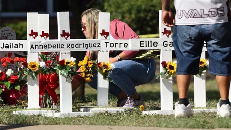 A mourner places flowers by each of the wooden crosses...