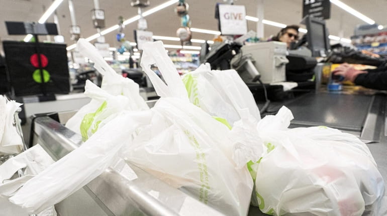 A customer's groceries are held in plastic bags at a...