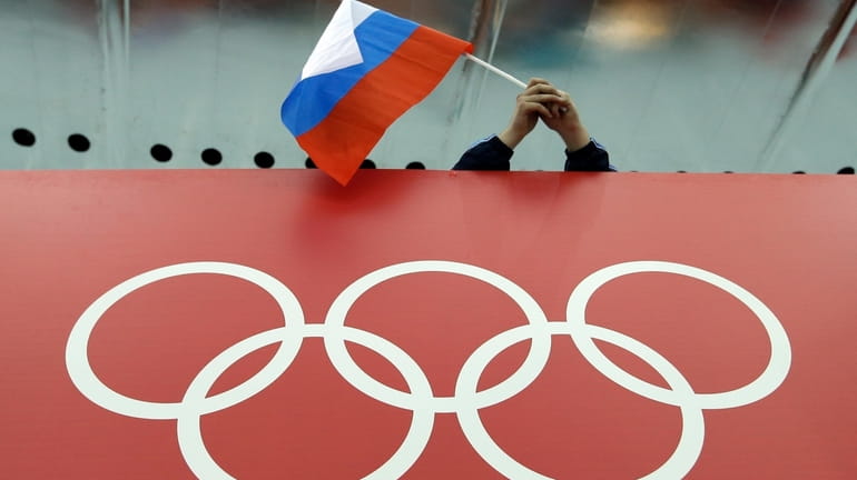 A Russian flag is held above the Olympic Rings at...