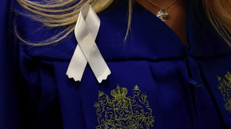 Hofstra University graduates wear white ribbons on their graduation gowns...