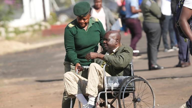 A prison officer escorts a freed elderly prisoner in a...