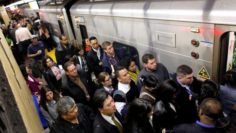 Passengers jam onto a train at Penn Station as LIRR...