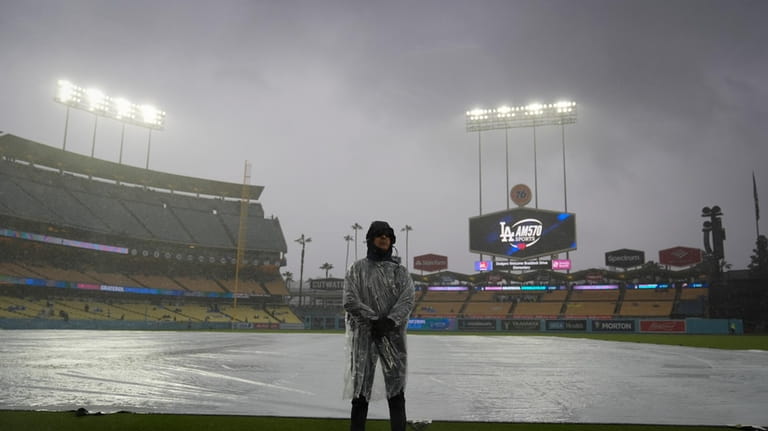 A security guard stands on the field in the rain...