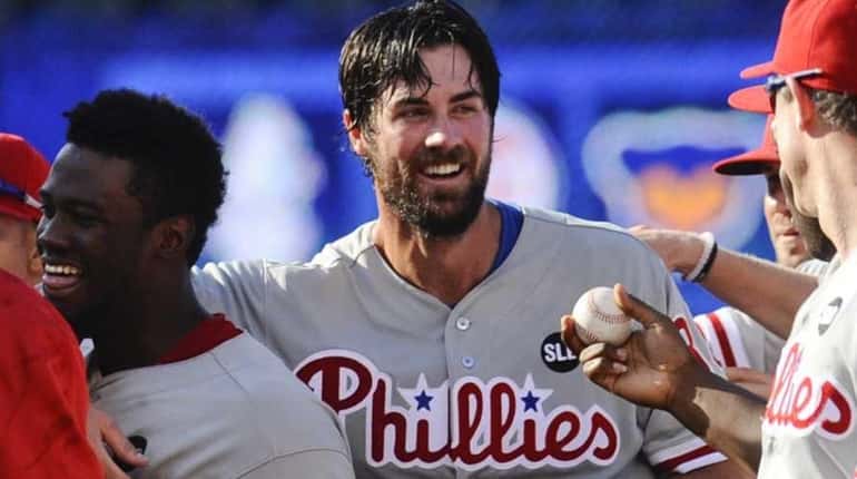 Philadelphia Phillies starting pitcher Cole Hamels, center, is handed the...