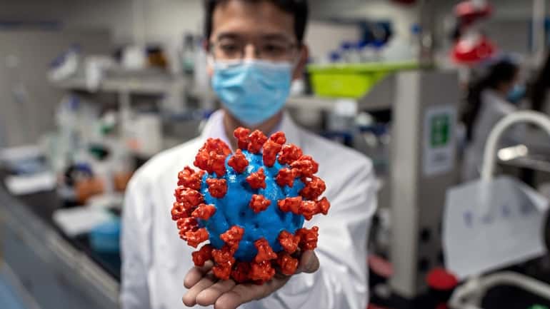 An engineer shows a plastic model of the COVID-19 coronavirus.