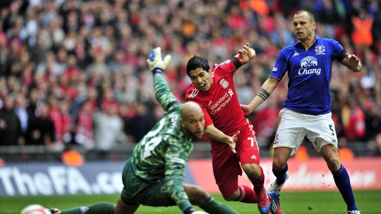 Liverpool striker Luis Suarez scores past Everton goalkeeper Tim Howard...