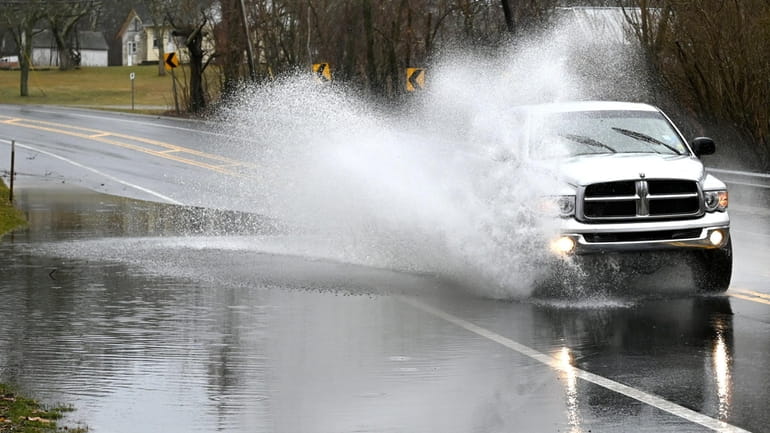 A vehicle drives through flooding on Montauk Highway on Saturday.