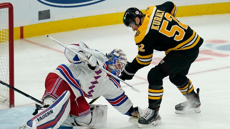 Rangers goaltender Keith Kinkaid covers the puck next to Bruins center...