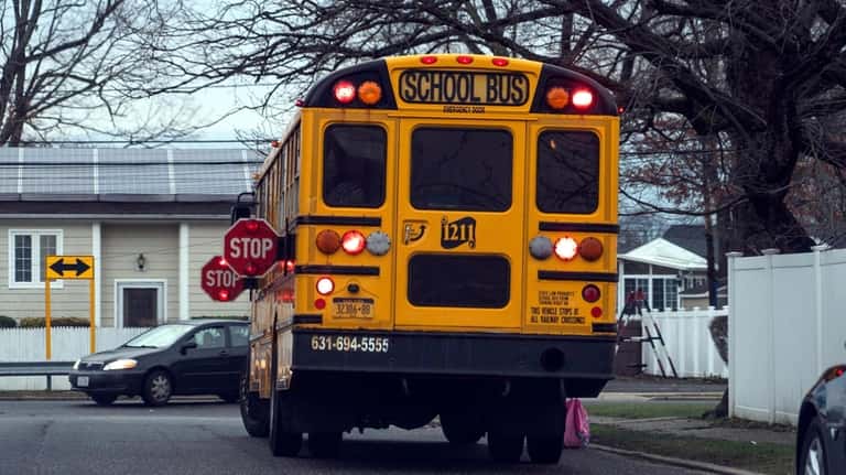 A school bus, with red lights and stop signs displayed,...