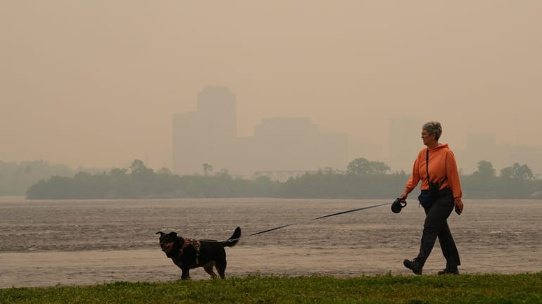 A woman walks her dog along the Ottawa River in...