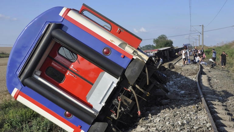 An overturned train car is seen near a village at...