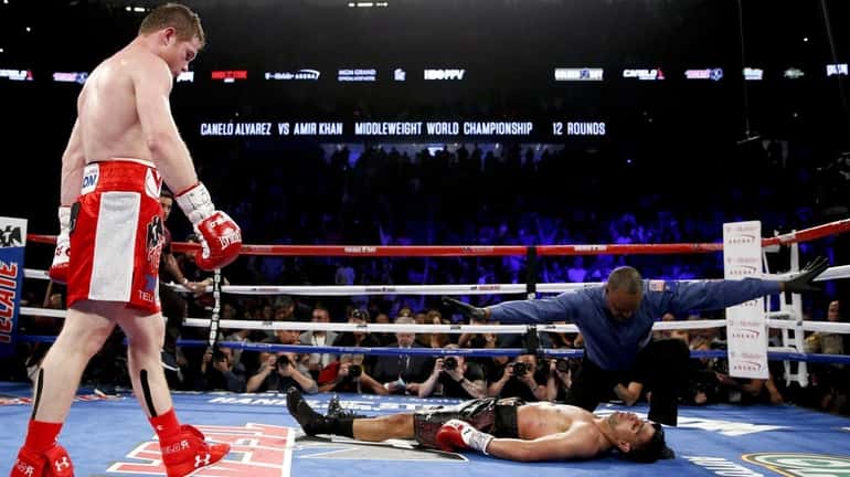 Canelo Alvarez, left, watches after knocking down Amir Khan during...