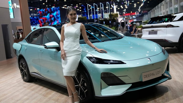 A model stands next to CHANGAN's electric vehicle "Deepal LO7"...