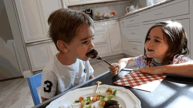 Maya Coppersmith, 4, feeds falafel to her brother Evan, 2,...