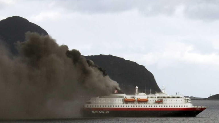 Norwegian cruise ship, MS Nordlys, billows smoke as it approaches...