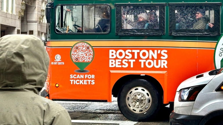 Visitors on a bus tour view downtown Boston through rain-splattered...