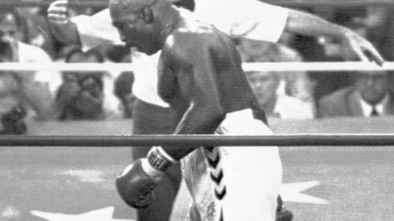 Earnie Shavers stands over Larry Holmes in the ninth round...