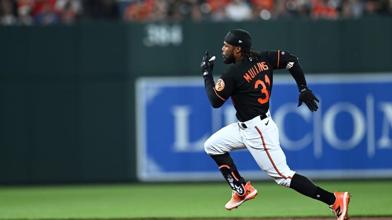 Baltimore Orioles' Cedric Mullins races to third on a triple...