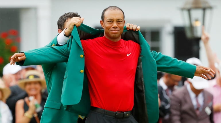 Tiger Woods is awarded the green jacket by Masters champion...