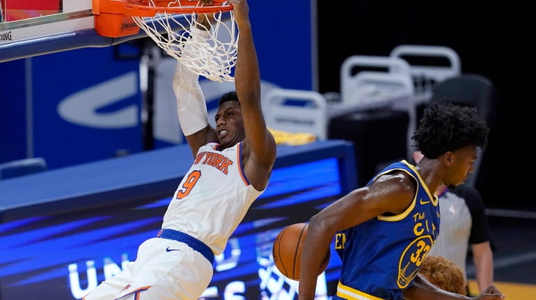 New York Knicks guard RJ Barrett hangs from the rim after...