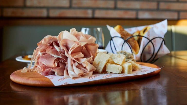 A meat and cheese board with Prosciutto di Parma, mortadella,...