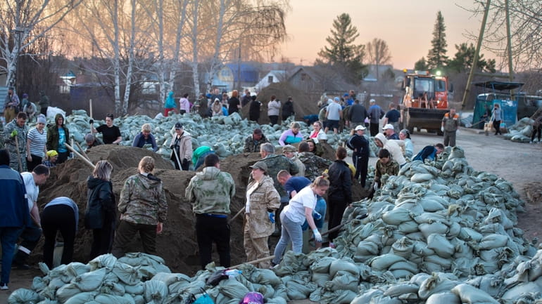 Local residents and volunteers prepare sandbags to strengthen the dam...