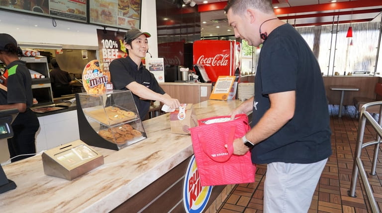 Burger King employee Carlos Urrutia of Wantagh, left, fills a...