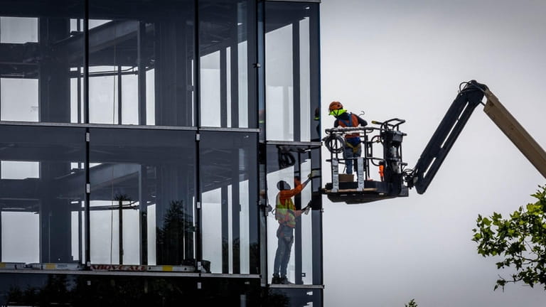 Two workers, one on a cherry picker and the other inside a...