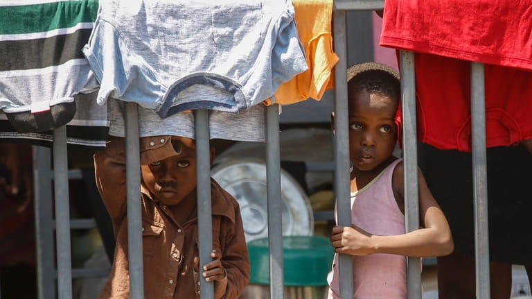 Children look through a fence at a shelter for families...