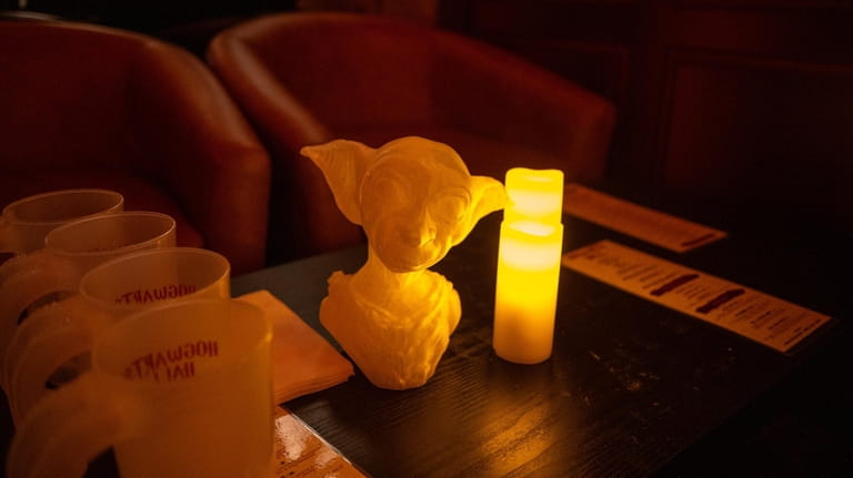 A candle is placed next to a Dobby figurine at...