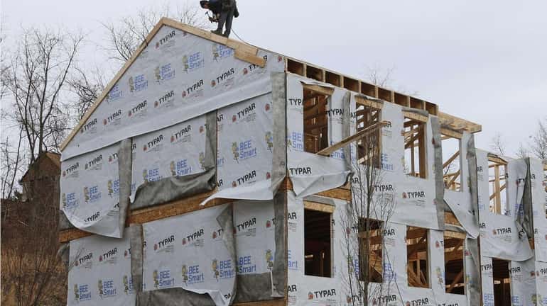A carpenter works on a home Monday in Robinson Township,...