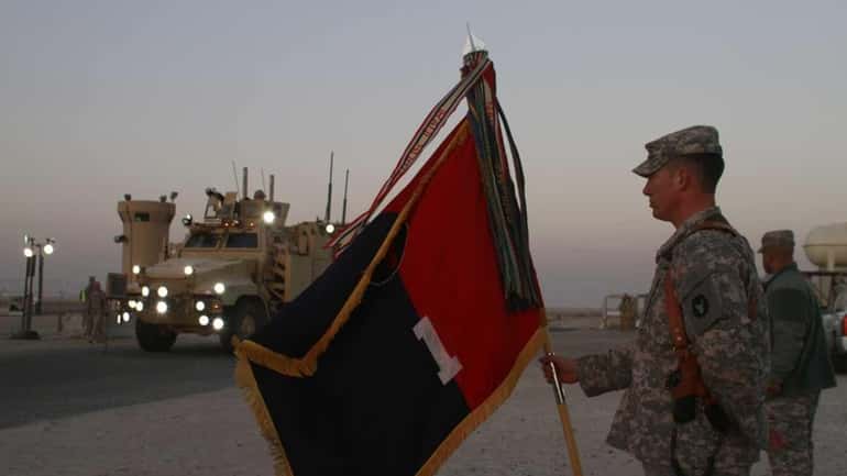 A U.S. Army soldier holds a flag as a convoy...