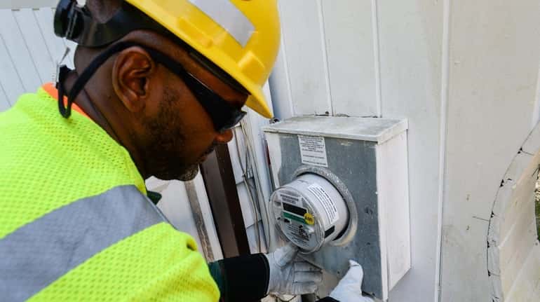 Neil Jackson, lead meter technician with PSEG Long Island, installs...