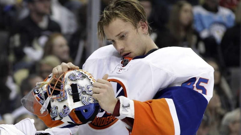 New York Islanders goalie Anders Nilsson adjusts his mask during...